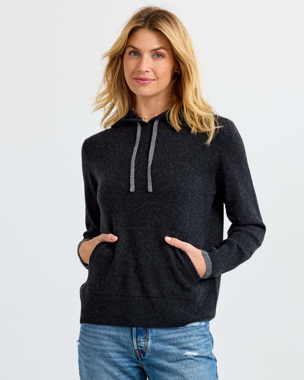 LIFESTYLE / EDITORIAL: Woman wearing charcoal gray cashmere hoodie with front pockets and drawstrings, paired with blue jeans