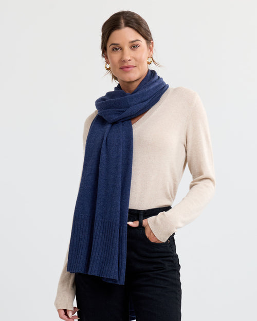 LIFESTYLE / EDITORIAL: Woman wearing indigo cashmere scarf and beige sweater against plain background