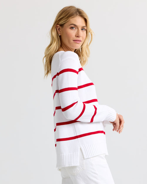 Side profile image of a woman wearing a white cashmere sweater with red stripes, looking over her shoulder.