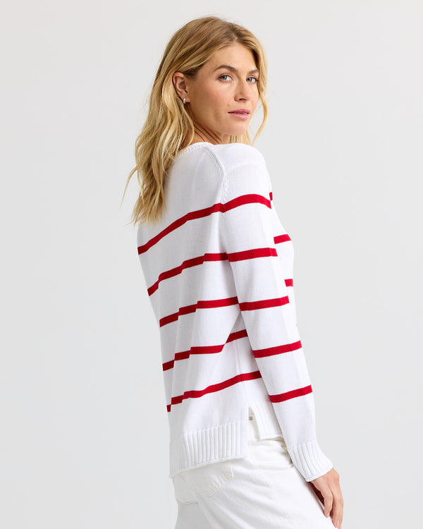 Side view image of a woman wearing a white and red striped cashmere sweater, looking back over her shoulder.