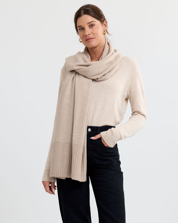 LIFESTYLE / EDITORIAL: Woman wearing beige cashmere sweater and scarf with black pants against white background