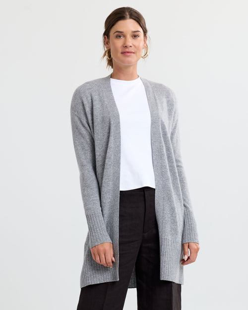 Front view image of a woman wearing a long grey open-front cashmere cardigan over a white top and black pants