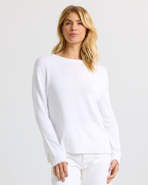 LIFESTYLE / EDITORIAL: Woman wearing white cashmere sweater and pants against plain light background