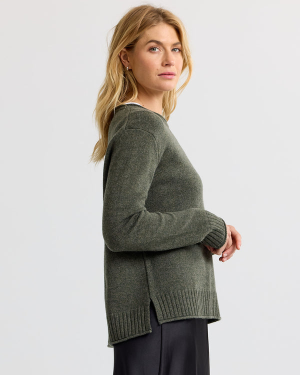 LIFESTYLE / EDITORIAL: Woman in dark olive cashmere sweater, side view, against plain light background