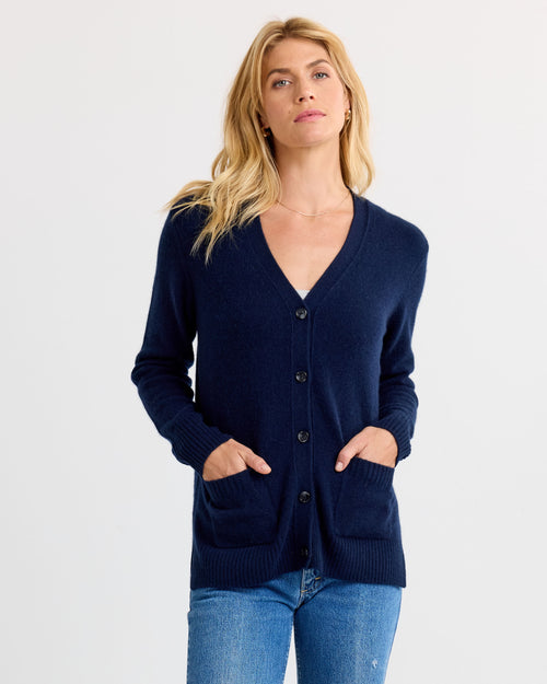 LIFESTYLE / EDITORIAL: Woman wearing navy blue cashmere cardigan with pockets and buttons, paired with blue jeans