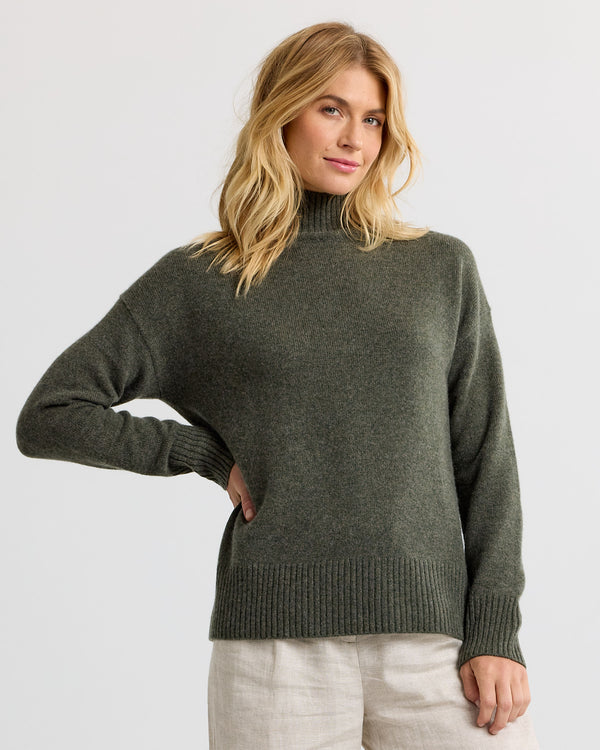 Dark olive cashmere funnel neck sweater with light trousers, three-quarter view