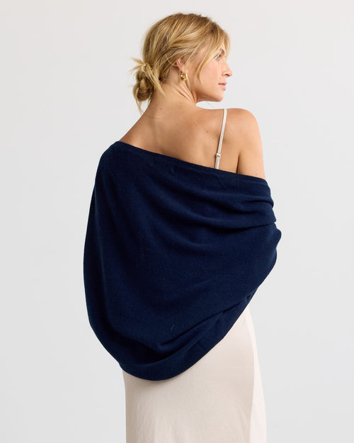 LIFESTYLE / EDITORIAL: Woman with blonde hair wearing navy cashmere shawl over beige dress, viewed from back and side profile