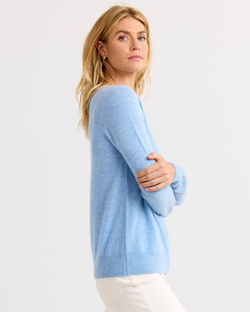 LIFESTYLE / EDITORIAL: Woman wearing light blue cashmere sweater, standing sideways against white background