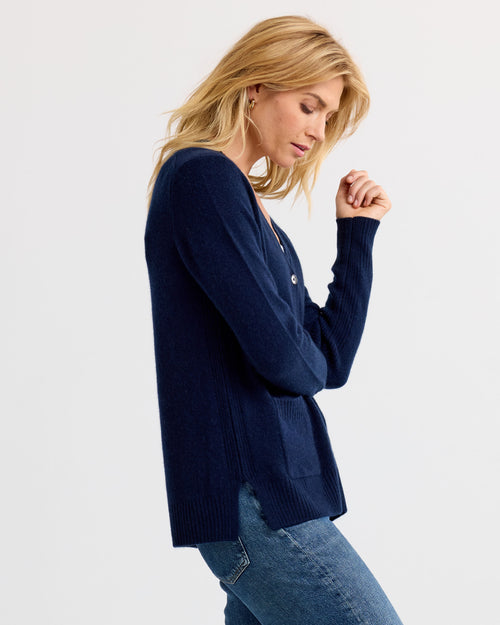 Woman in navy cashmere cardigan and jeans, side view, plain background