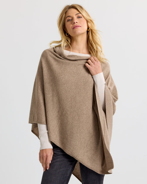LIFESTYLE / EDITORIAL: Woman wearing a driftwood-colored cashmere poncho over a white long-sleeve top and dark pants