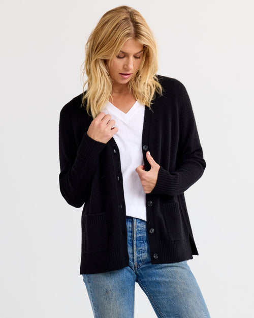 LIFESTYLE / EDITORIAL: Woman wearing black cashmere cardigan over white V-neck shirt and blue jeans against white background