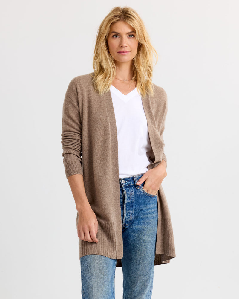 LIFESTYLE / EDITORIAL: Woman wearing driftwood-colored long cashmere cardigan, white V-neck shirt, and blue jeans against