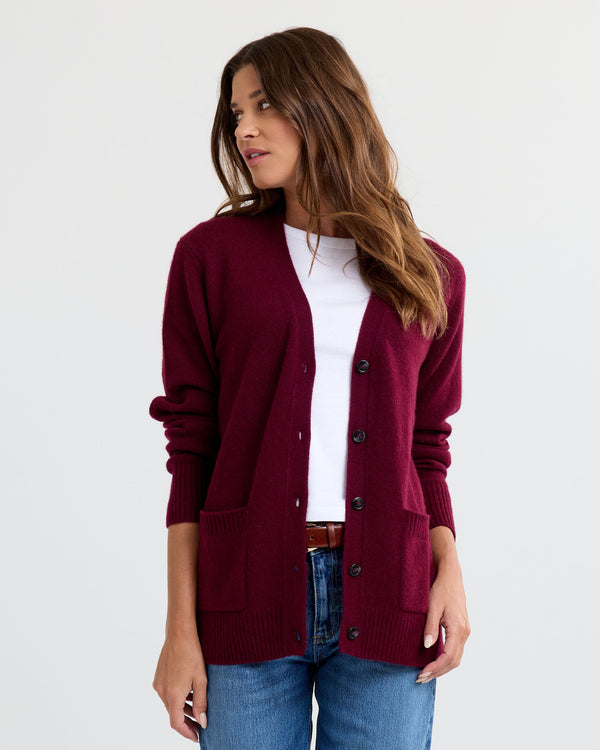 Three-quarter view image of a woman wearing a cabernet cashmere cardigan over a white top and blue jeans.