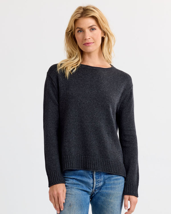 Front view image of a woman wearing a charcoal cashmere sweater paired with blue jeans against a plain background