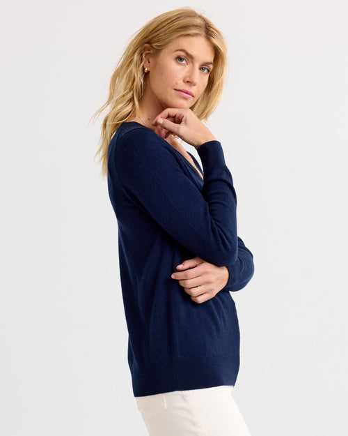 LIFESTYLE / EDITORIAL: Woman in navy cashmere sweater and white pants posing against plain background