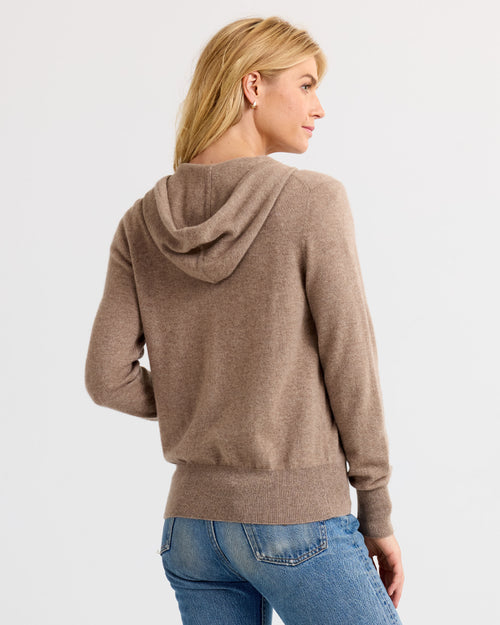 Woman wearing driftwood-colored cashmere hoodie, back view, paired with blue jeans against white background