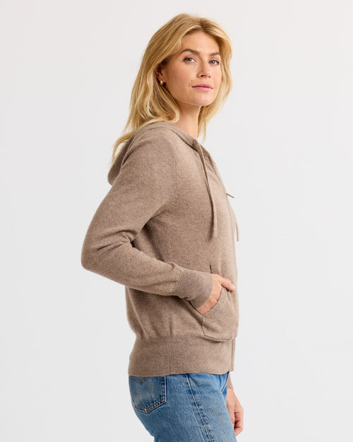 LIFESTYLE / EDITORIAL: Woman in driftwood-colored cashmere hoodie and blue jeans, side view, neutral background