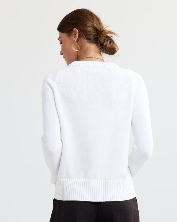 LIFESTYLE / EDITORIAL: Woman wearing cream cashmere sweater, back view, hair in bun, gold hoop earrings, white background