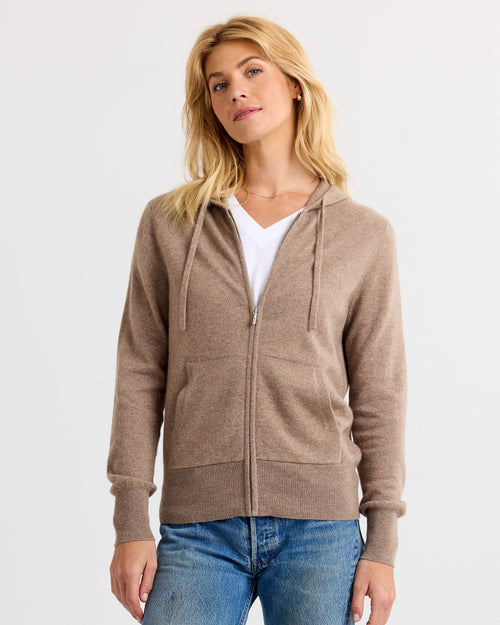 LIFESTYLE / EDITORIAL: Woman wearing driftwood brown zip-up cashmere hoodie and white V-neck shirt with blue jeans against
