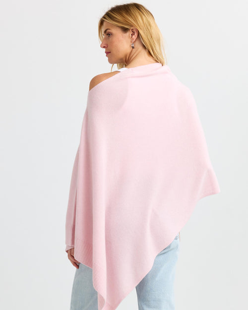 LIFESTYLE / EDITORIAL: Woman wearing blush pink cashmere poncho, viewed from back, paired with light blue jeans