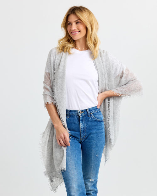 LIFESTYLE / EDITORIAL: Woman wearing light gray cashmere shawl over white tee and blue jeans, smiling and posing against