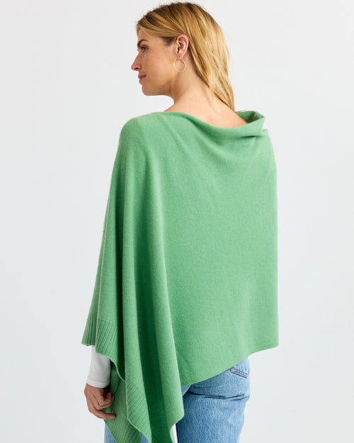 LIFESTYLE / EDITORIAL: Woman wearing green cashmere poncho and jeans, viewed from back against white background