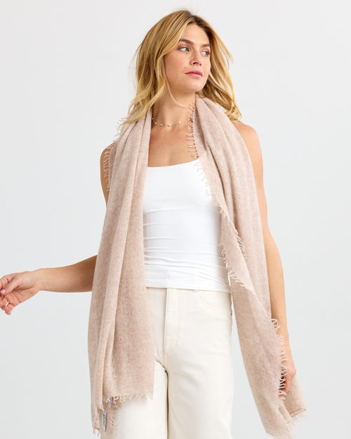 LIFESTYLE / EDITORIAL: Woman wearing light beige cashmere scarf over white top and cream pants against white background