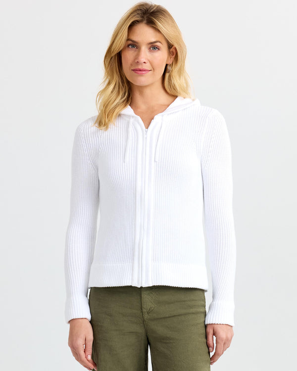 LIFESTYLE / EDITORIAL: Woman wearing white zip-up ribbed cashmere hoodie and olive pants against plain background
