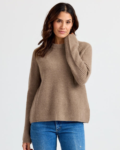Front view image of a woman wearing a driftwood ribbed cashmere sweater with blue jeans against a white background