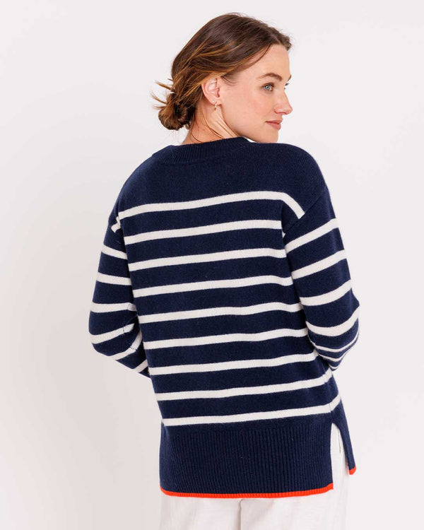 LIFESTYLE / EDITORIAL: Woman wearing navy and ivory striped cashmere sweater with orange hem, viewed from back