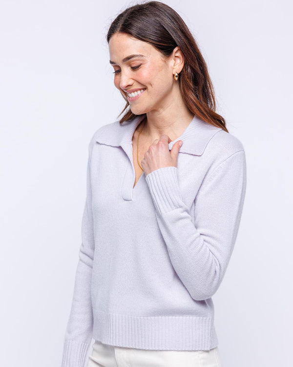 LIFESTYLE / EDITORIAL: Woman smiling wearing lilac frost cashmere polo sweater with ribbed cuffs and hem against white