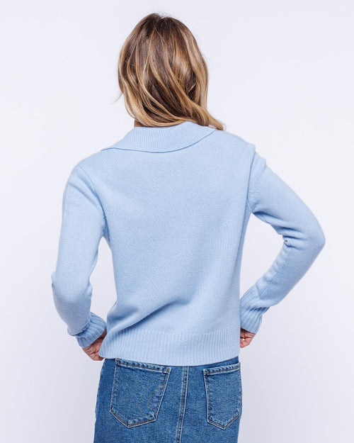 Woman wearing powder blue cashmere polo crew sweater, shown from back, paired with blue denim jeans