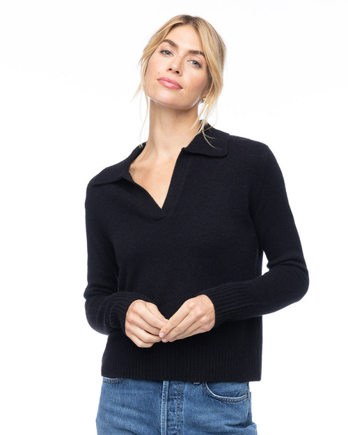 LIFESTYLE / EDITORIAL: Woman wearing black V-neck cashmere polo sweater and blue jeans against white background