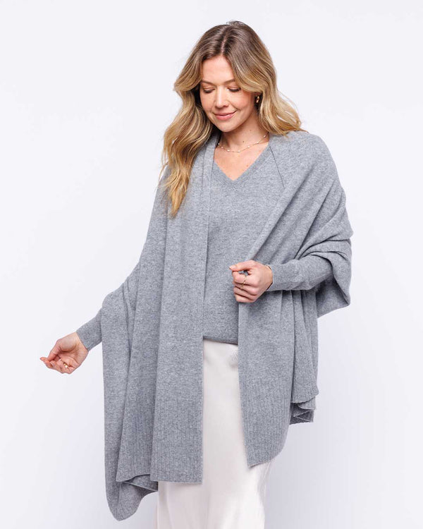 LIFESTYLE / EDITORIAL: Woman wearing a light gray cashmere wrap and sweater with white skirt against white background