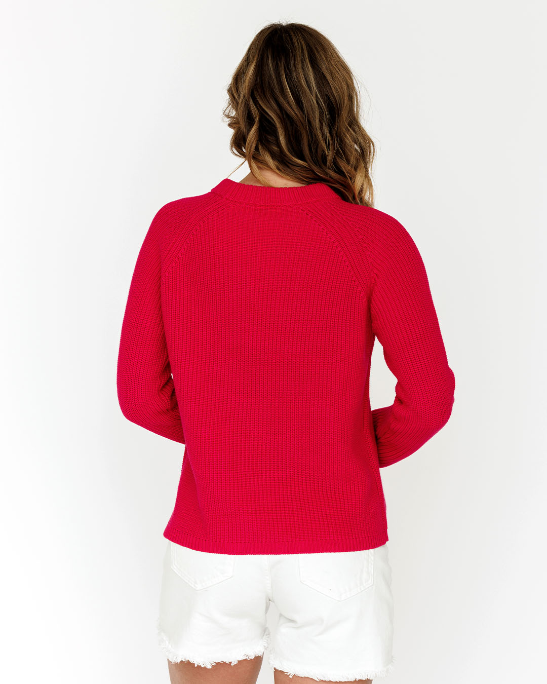 LIFESTYLE / EDITORIAL: Woman wearing bright red sweater and white shorts, shown from the back against a white background