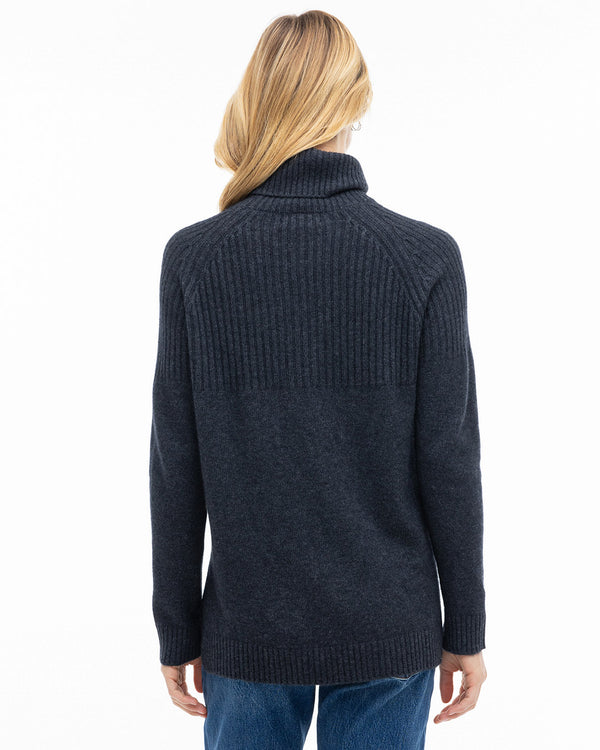 Rear view image of a woman wearing a charcoal half-rib turtleneck cashmere sweater with blue jeans