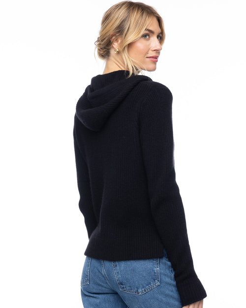LIFESTYLE / EDITORIAL: Woman wearing black cashmere fisherman hoodie, shown from back, paired with blue jeans