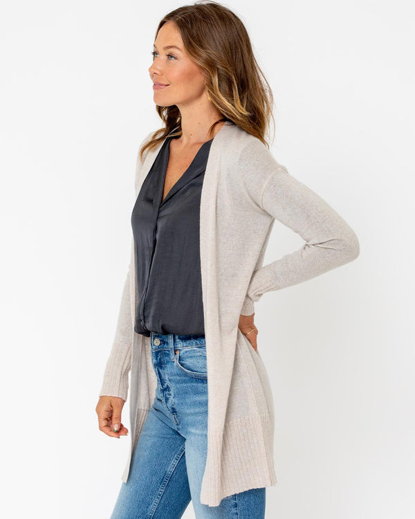 LIFESTYLE / EDITORIAL: Woman wearing long beige cashmere cardigan over black blouse and blue jeans, standing sideways