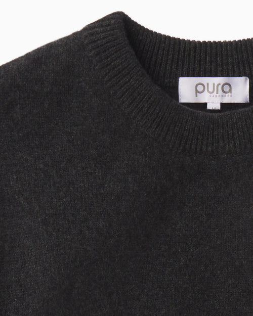 Close-up of charcoal-colored cashmere crew neck sweater with ribbed collar and "pura cashmere" label visible