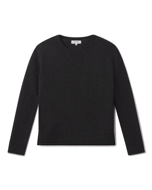 Black crewneck cashmere sweater with long sleeves and ribbed cuffs and hem, laid flat on white background