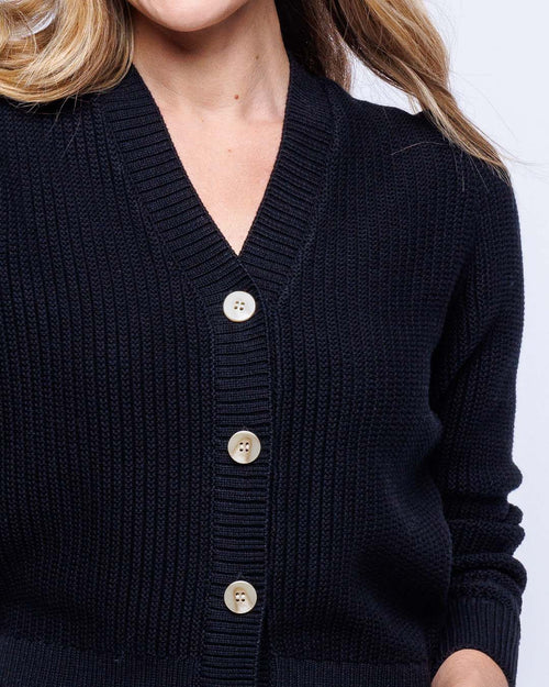 Close-up of black textured knit cardigan with three beige buttons on model's torso