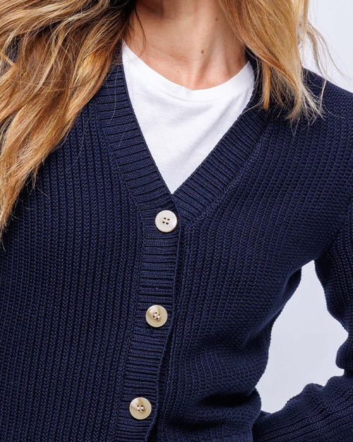 Close-up of navy textured knit cardigan with beige buttons worn over white t-shirt