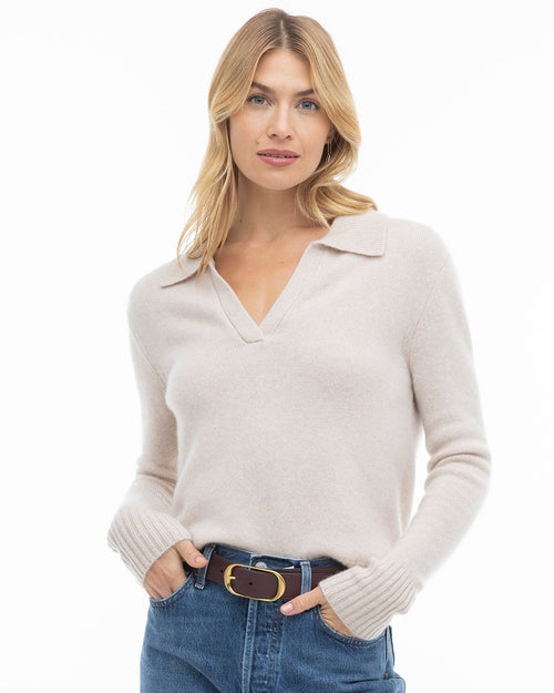 LIFESTYLE / EDITORIAL: Woman wearing oatmeal cashmere V-neck sweater with collar and blue jeans against white background