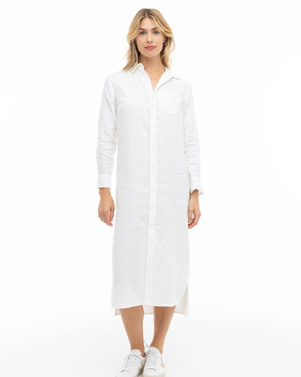 LIFESTYLE / EDITORIAL: Woman wearing a long white button-down dress and white sneakers, standing against a white background