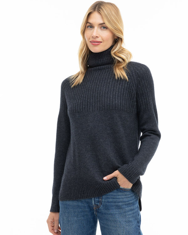 Front view image of a woman wearing charcoal cashmere turtleneck sweater paired with blue jeans against white background