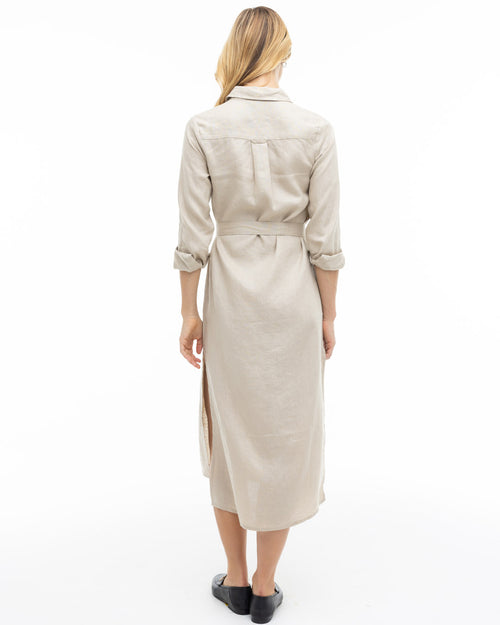 Woman wearing a sandstone-colored long cashmere dress with rolled sleeves, viewed from the back against a white background