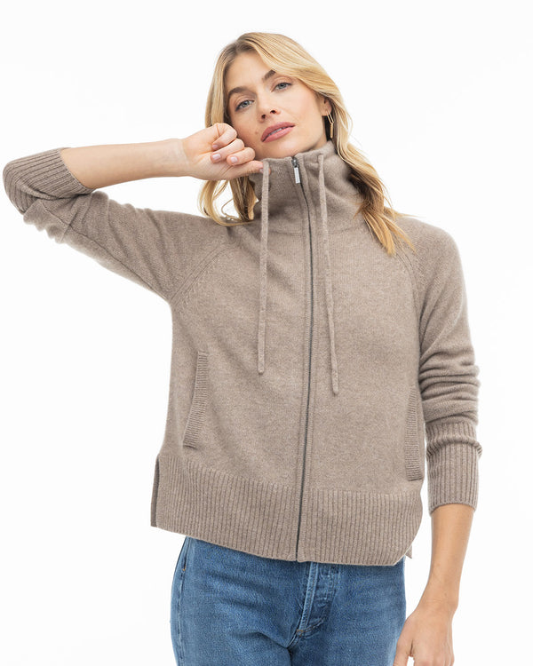 LIFESTYLE / EDITORIAL: Woman wearing a zip-up driftwood-colored cashmere sweater with high collar and blue jeans against