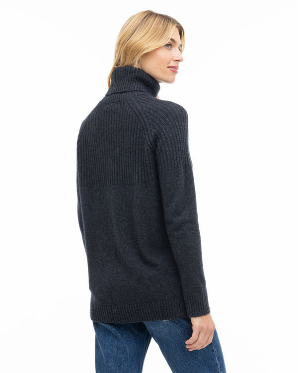LIFESTYLE / EDITORIAL: Woman wearing charcoal turtleneck cashmere sweater, shown from back, paired with blue jeans