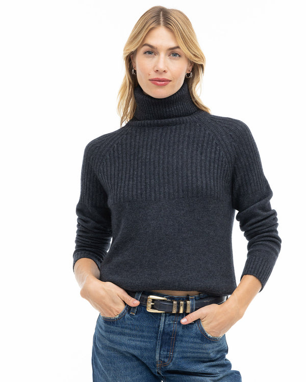 LIFESTYLE / EDITORIAL: Woman wearing charcoal turtleneck cashmere sweater and blue jeans with hands in pockets