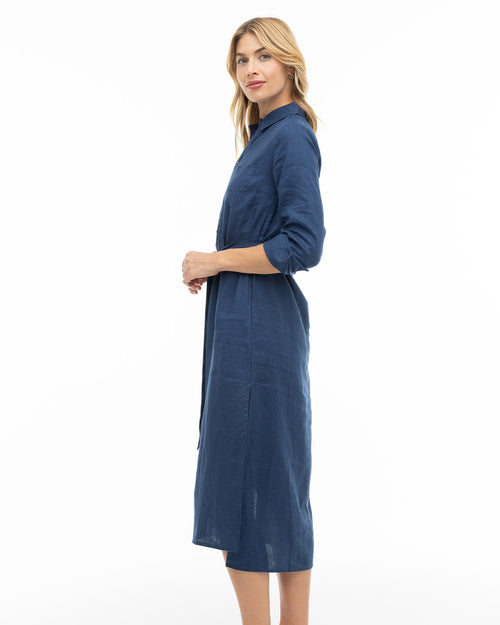 Woman in navy blue long-sleeve midi dress standing sideways against white background